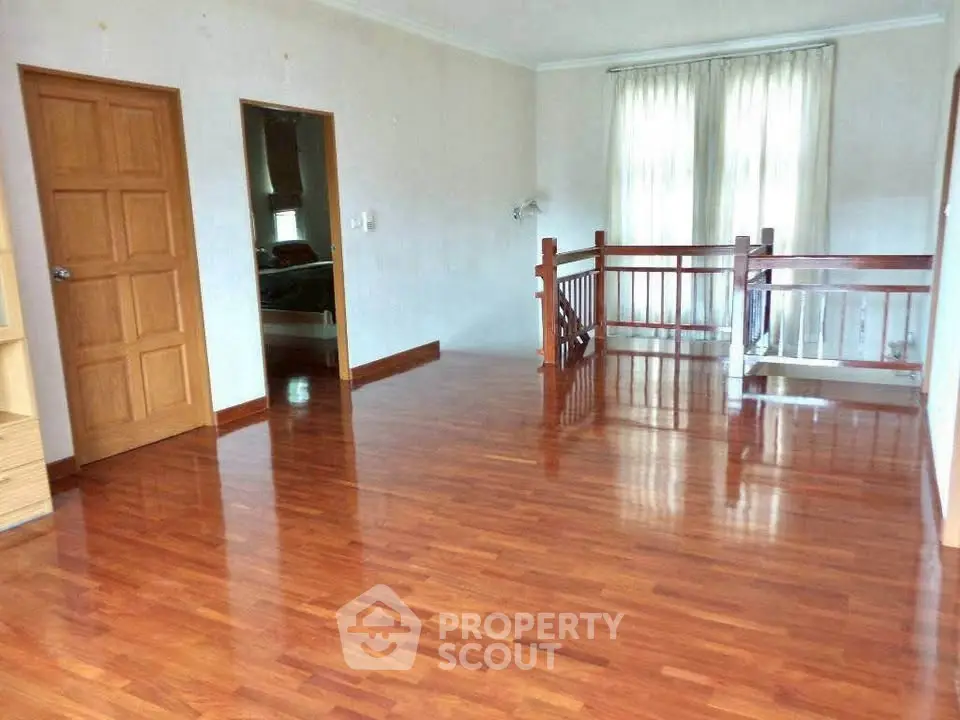 Spacious hardwood floor room with natural light and wooden railing.
