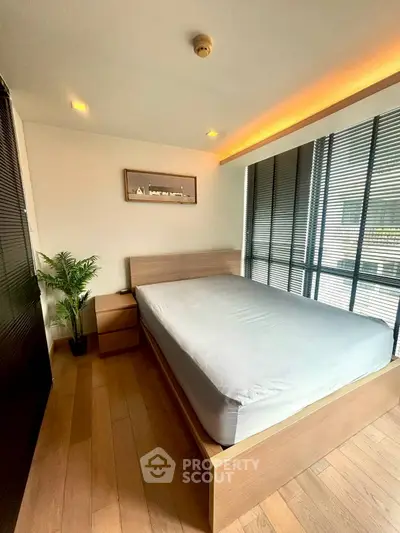 Modern bedroom with large windows and wooden flooring in a stylish apartment.