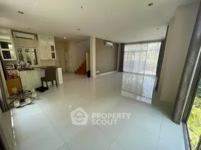 Spacious open-plan living room with large windows and modern interior design.