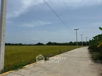 Expansive land plot with clear skies and paved road access, ideal for development.