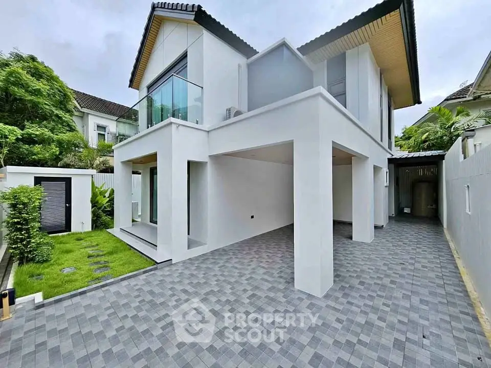 Modern two-story house with sleek design and spacious driveway in a lush green setting.