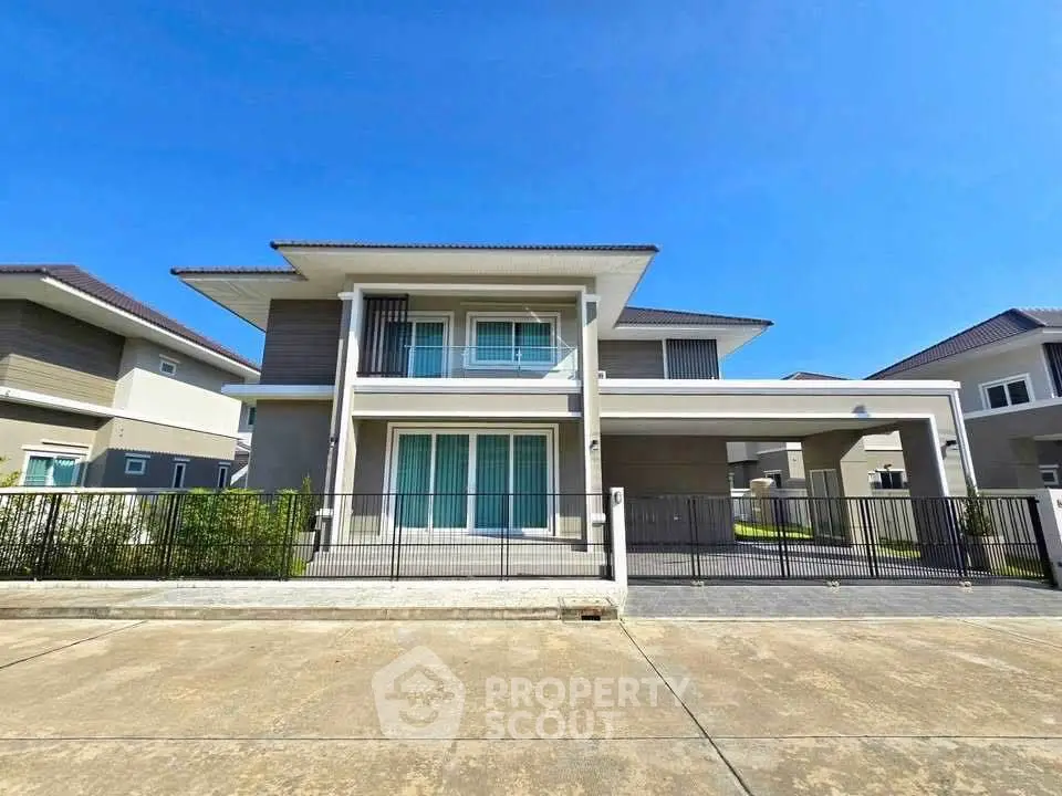 Modern two-story house with sleek design and spacious driveway under clear blue sky.