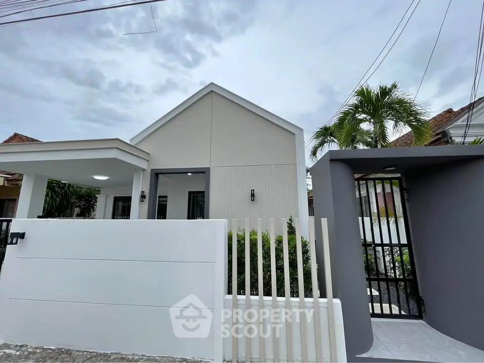 Modern minimalist house exterior with sleek white walls and lush greenery.