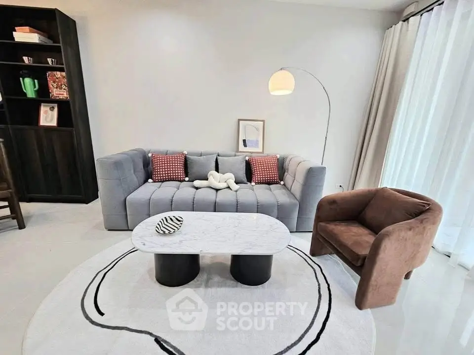 Modern living room with stylish furniture and elegant decor, featuring a cozy sofa and chic armchair.