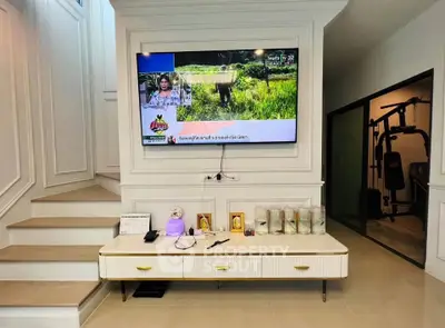 Modern living room with wall-mounted TV and gym equipment, stylish decor and sleek design.