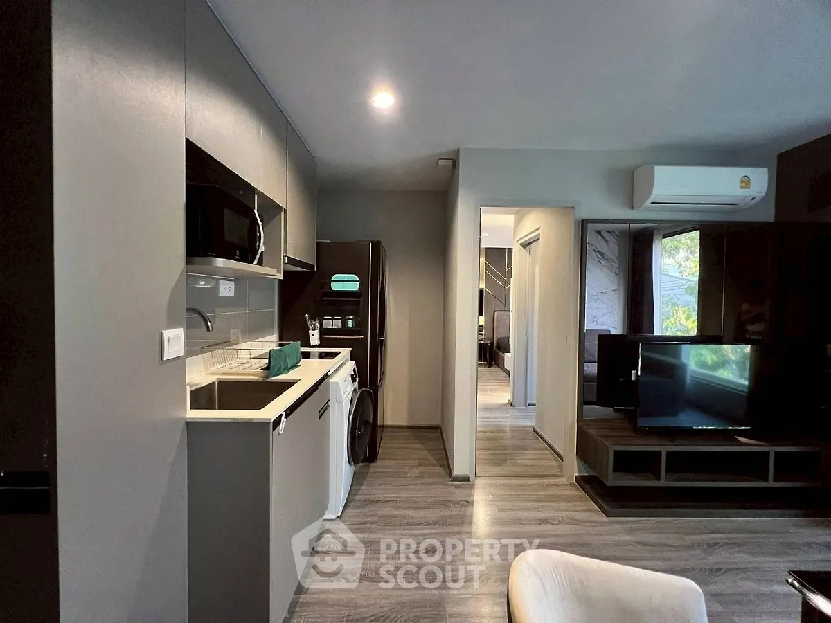 Modern apartment interior with sleek kitchen and cozy living area, featuring stylish appliances and contemporary design.