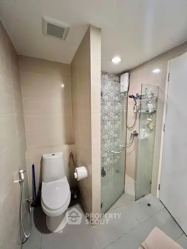 Modern bathroom with glass shower enclosure, neutral tile walls, and sleek fixtures, offering a clean and contemporary living space.