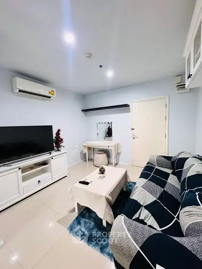 Cozy living room with modern decor, featuring a large TV, stylish sofa, and air conditioning.