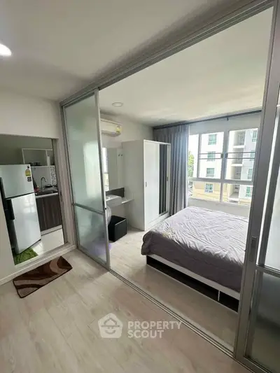 Modern bedroom with large windows and sliding glass doors in a stylish apartment.