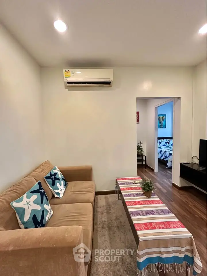 Cozy living room with modern decor and air conditioning, leading to a stylish bedroom.