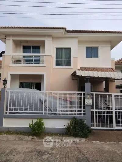 Charming two-story house with balcony and gated driveway in a serene neighborhood.