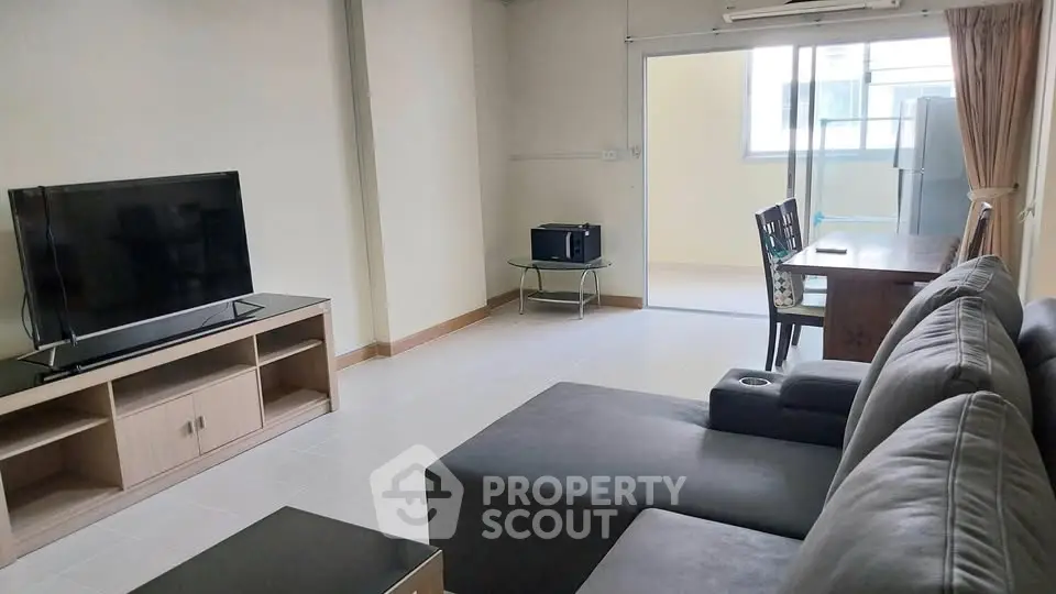 Spacious living room with modern furniture and large TV, perfect for relaxation and entertainment.