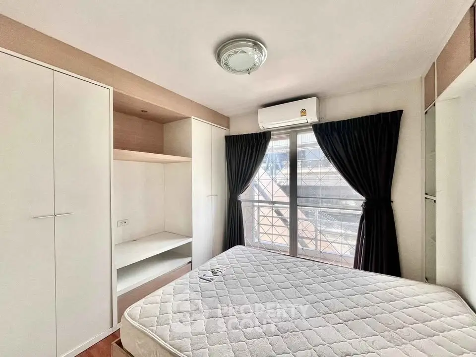 Bright bedroom with large window, built-in wardrobe, and air conditioning unit.