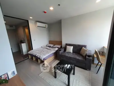 Modern studio apartment with cozy bed, stylish sofa, and natural light.