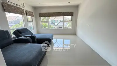 Spacious living room with large windows and modern furniture, offering abundant natural light and a serene view.