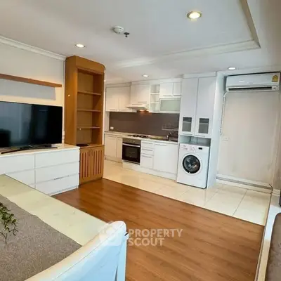 Modern open-plan living room with kitchen, featuring sleek appliances and cozy ambiance.