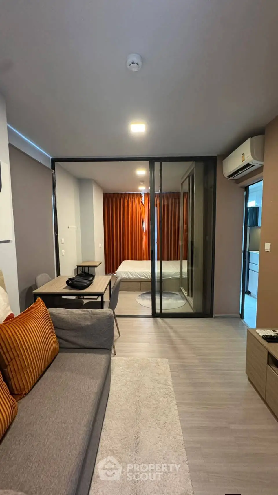 Modern studio apartment with glass partition, cozy living area, and stylish decor.