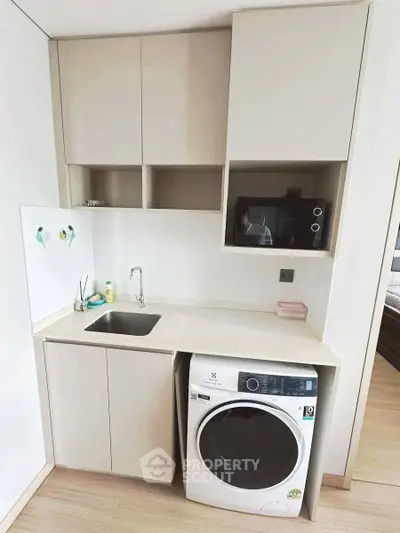 Compact kitchen with modern appliances and washing machine in a cozy apartment.