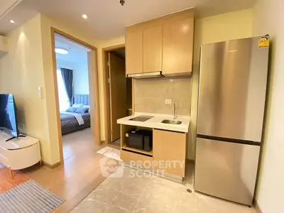 Modern apartment kitchen with sleek fridge and cozy bedroom view