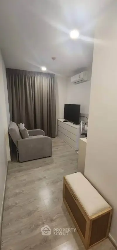Cozy living room with modern decor and natural light, featuring a comfortable armchair and sleek TV setup.