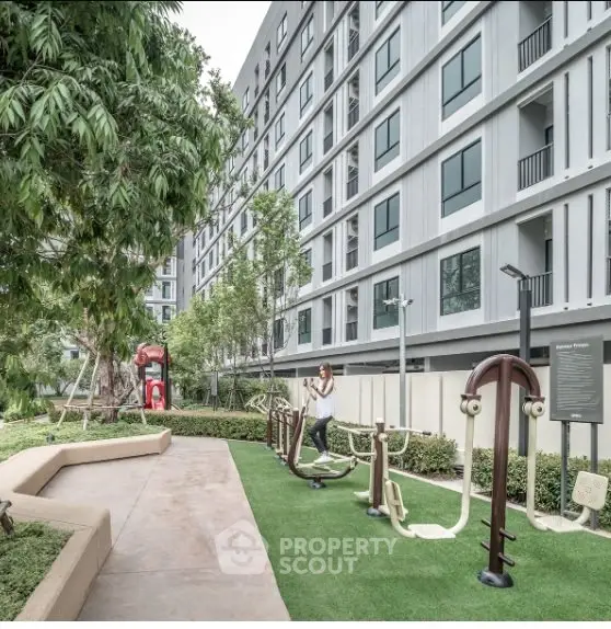 Modern apartment building with outdoor fitness area and lush greenery.