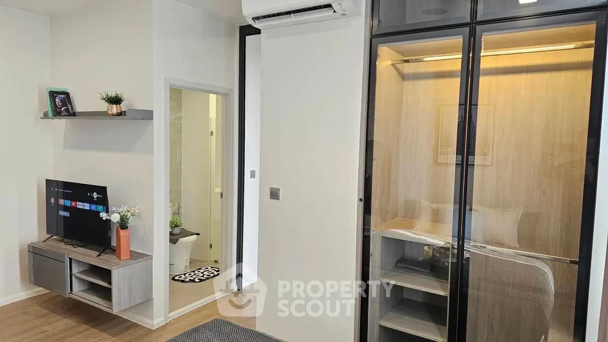 Modern living room with sleek TV unit and glass cabinet, showcasing contemporary interior design.