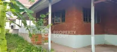 Charming rustic brick house with lush greenery and inviting porch.