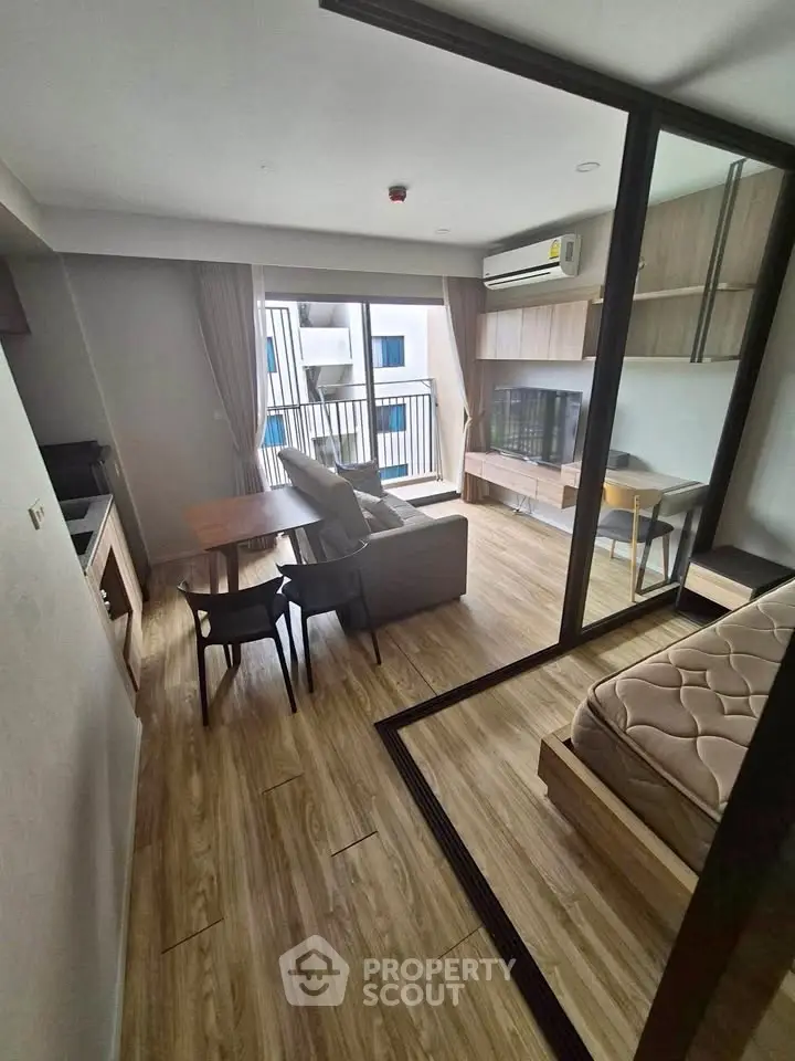 Modern studio apartment with open layout, featuring a cozy living area and a small balcony.
