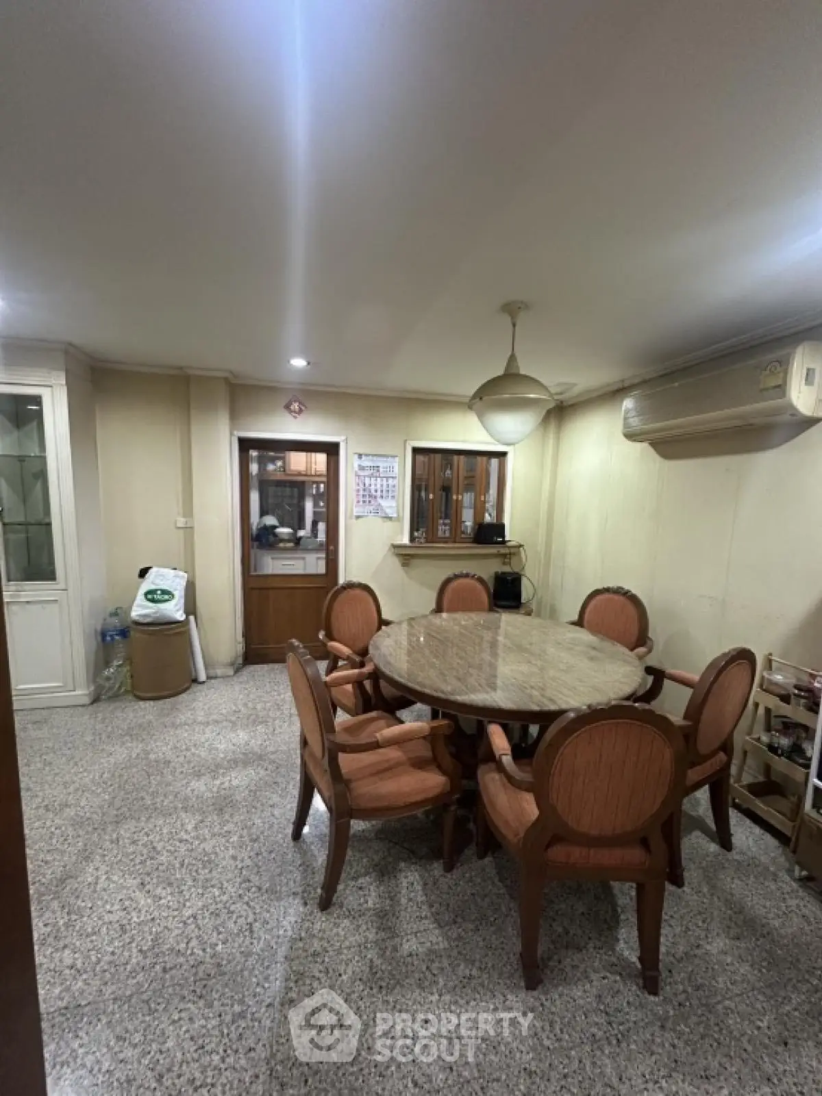 Spacious dining area with elegant round table and chairs, featuring air conditioning and ample lighting.