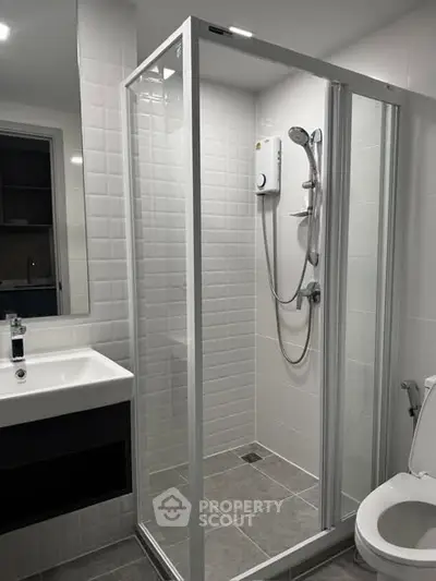 Modern bathroom with glass shower enclosure and sleek fixtures in a contemporary apartment.