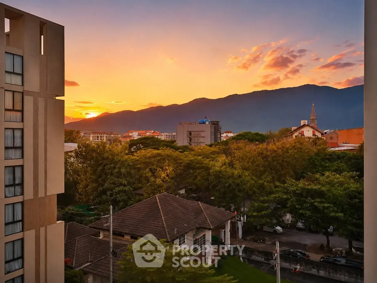 Stunning sunset view from a modern apartment building overlooking lush greenery and distant mountains.