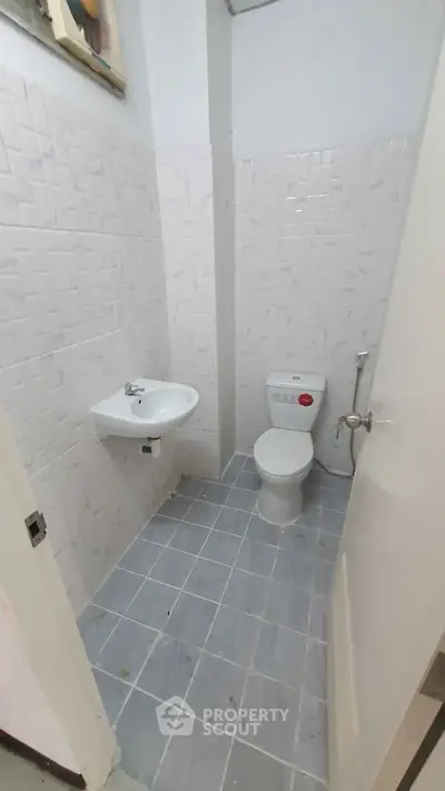 Compact bathroom with white tiles and basic fixtures, ideal for small spaces.