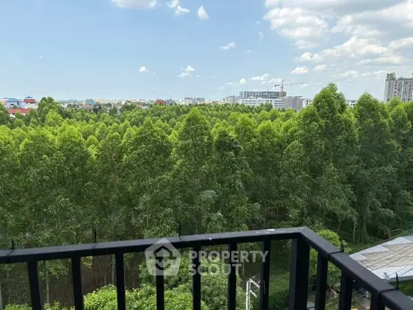 Stunning balcony view overlooking lush green forest and city skyline.