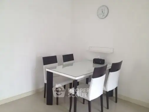 Minimalist dining area with sleek glass table and modern chairs.