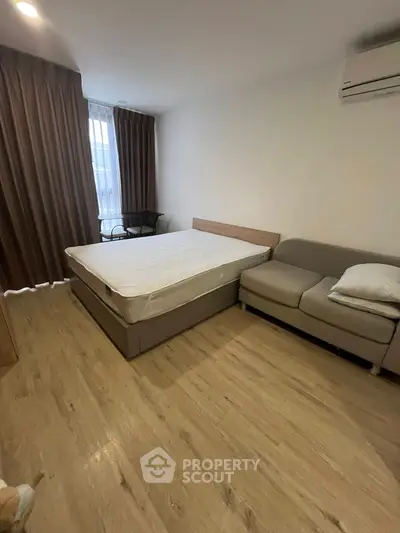 Cozy bedroom with modern furnishings and natural light, featuring a comfortable bed and stylish sofa.