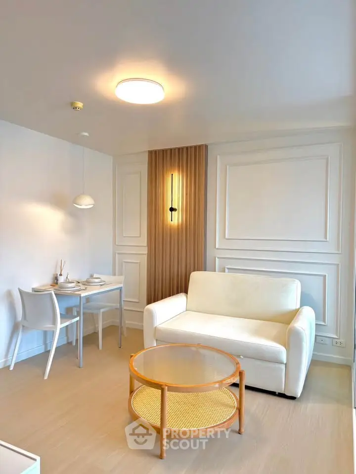 Modern living room with elegant white sofa, stylish lighting, and cozy dining area for two.