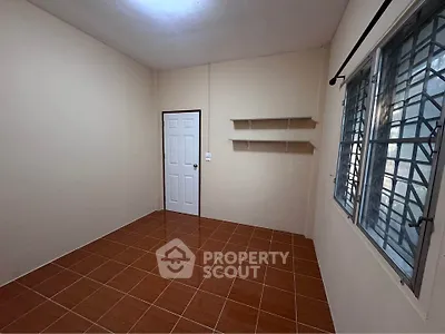 Spacious empty room with tiled floor and natural light from window