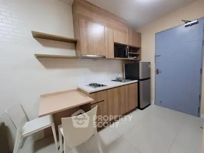 Modern compact kitchen with wooden cabinets and dining area in a cozy apartment.