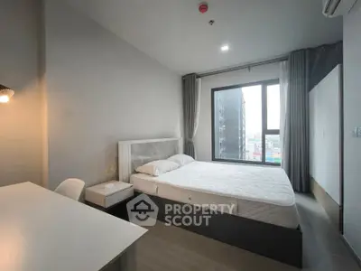 Modern bedroom with large window and city view, featuring a comfortable bed and sleek furniture.