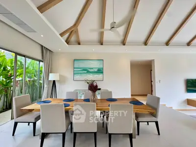 Spacious dining area with modern decor and garden view, featuring elegant wooden beams and stylish furniture.