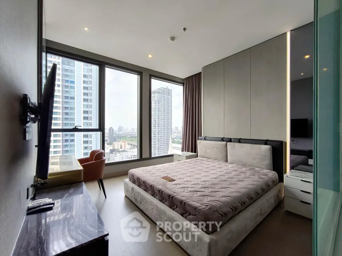 Modern bedroom with large windows offering stunning city views in a high-rise apartment.