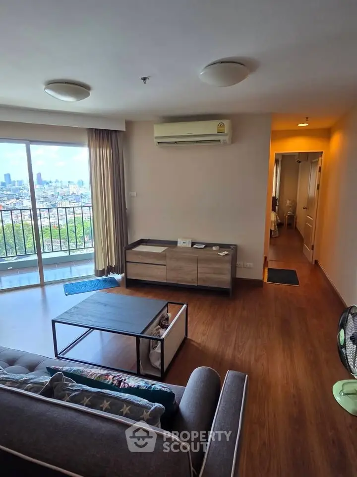 Spacious living room with city view and modern furnishings in high-rise apartment.