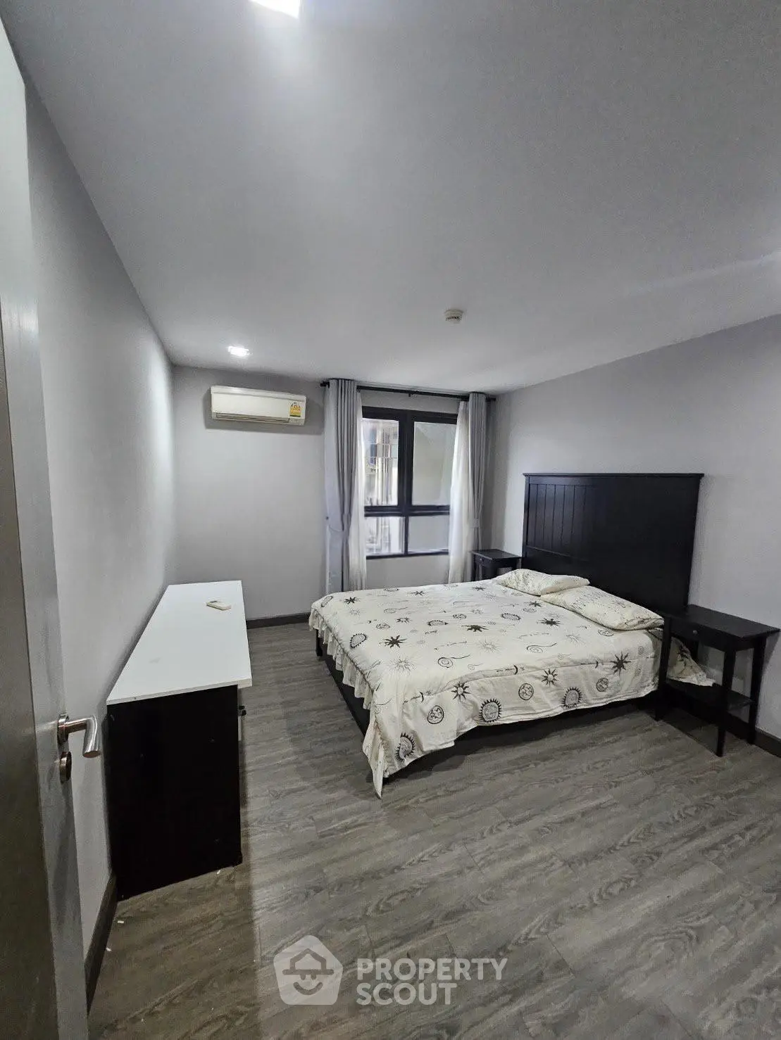 Spacious bedroom with modern decor and large window for natural light.