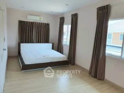 Spacious bedroom with large windows and modern decor in a serene residential area.