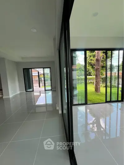 Spacious modern living room with large glass doors opening to a lush garden view, perfect for natural light.