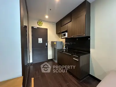 Modern kitchen with dark wood cabinets and sleek appliances in a cozy apartment.