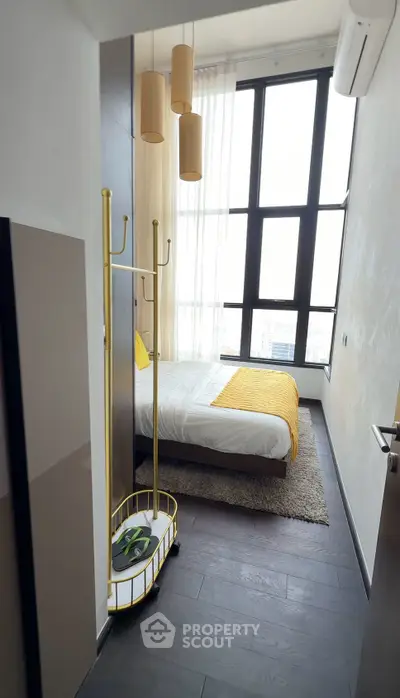 Modern bedroom with high ceilings and large windows, featuring stylish decor and natural light.