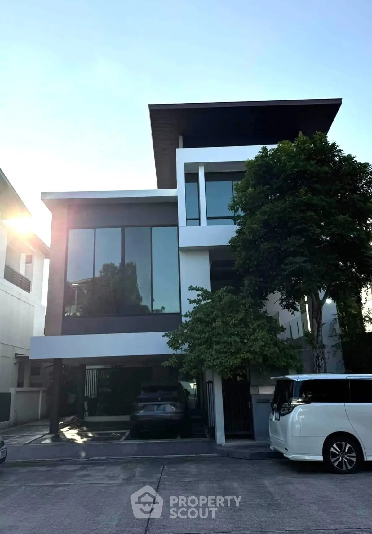 Modern three-story house with large windows and sleek design in urban setting.