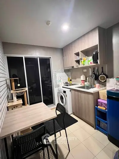 Modern kitchen with compact layout, featuring washing machine and sleek cabinetry.