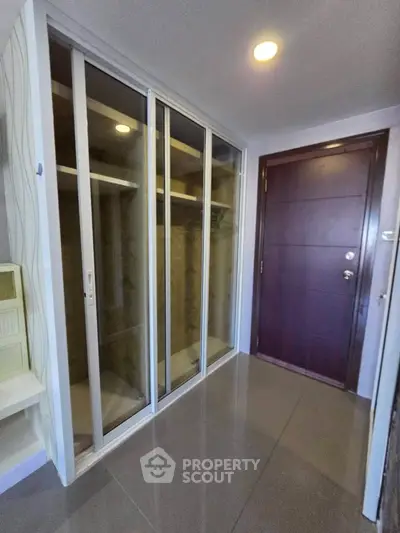Modern apartment entrance with sleek sliding closet and elegant wooden door
